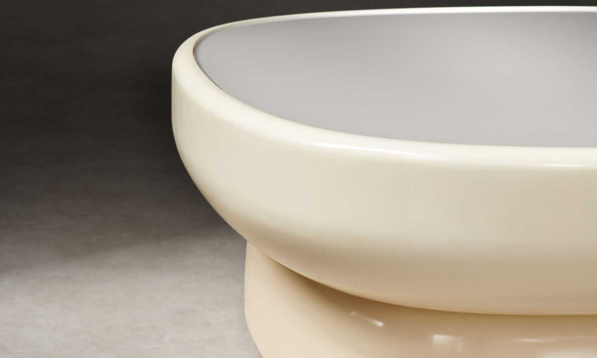 emile oval glass coffee table with lacquered beige base and white opaque glass top in art deco style, close up